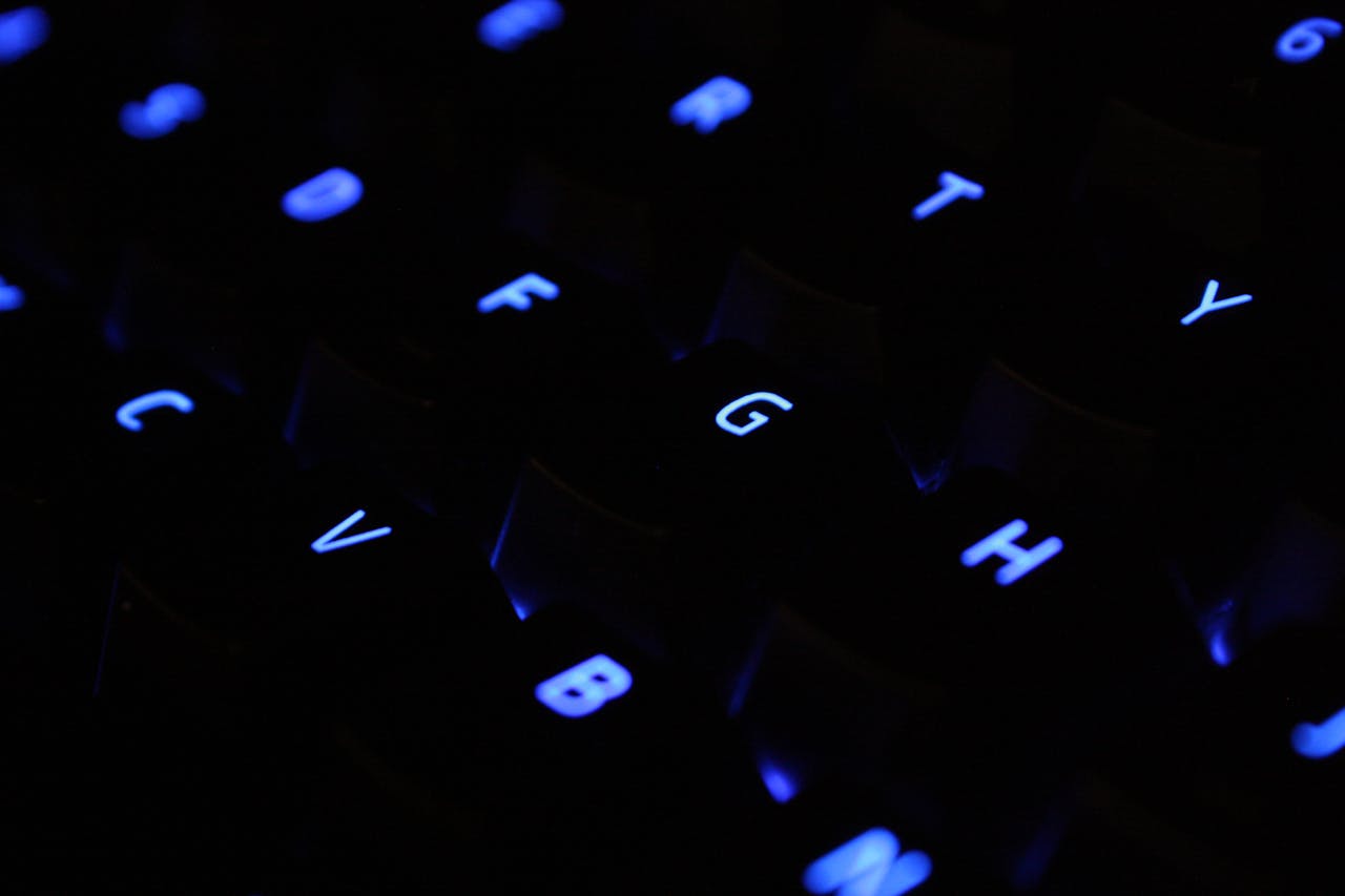 A detailed shot of blue backlit keyboard keys in a dark setting.