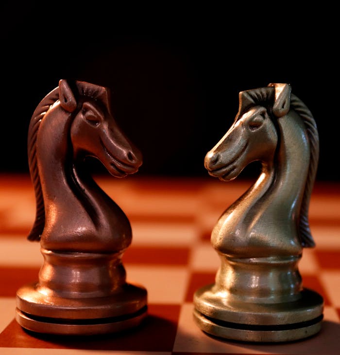 Crafting Captivating Headlines: Your awesome post title goes here Two chess knight pieces facing each other on a chessboard, dramatic lighting.